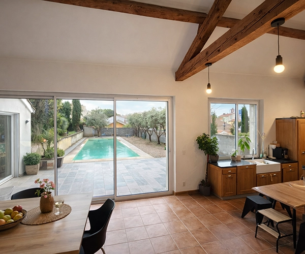 Rénovation intérieure cuisine avec poutres apparentes et vue piscine à Béziers